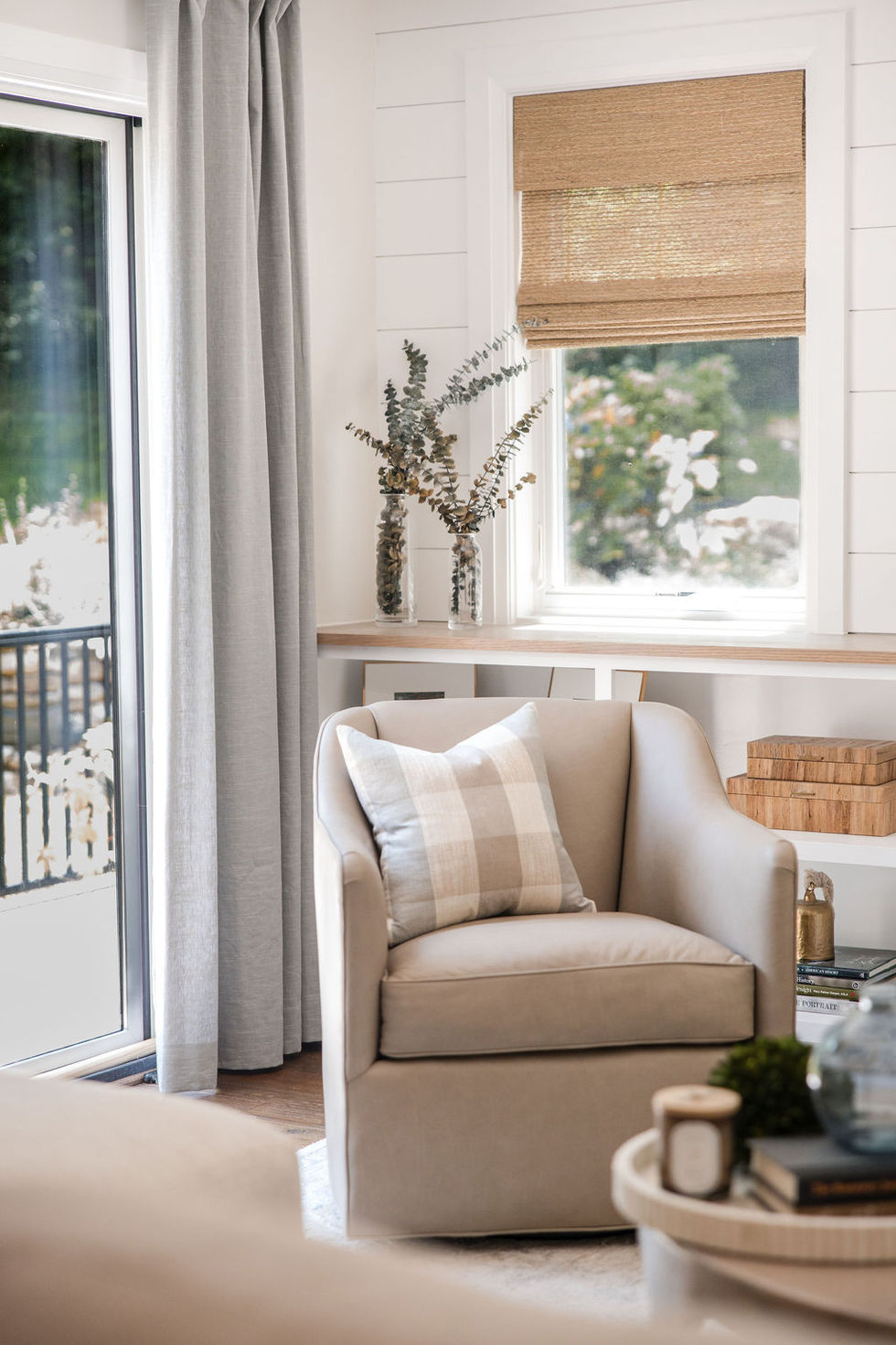 a chair with a plaid pillow sits in front of a window