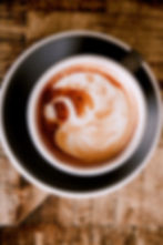 A cup of coffee with coffee art in the form of a swan