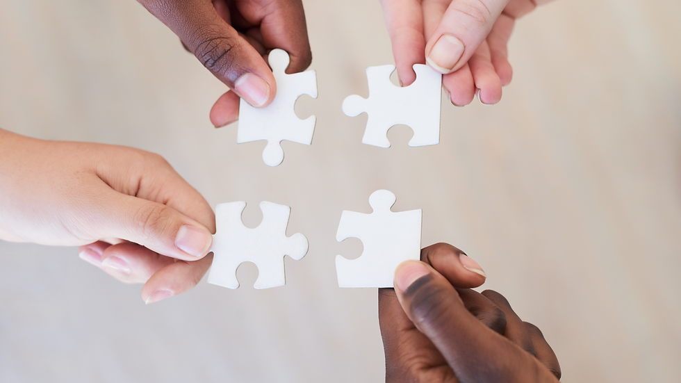 Four diverse hands each hold a puzzle piece, symbolizing the bringing together of all of the changes in the dyslexia definition. 