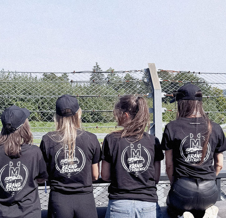 Ein Teil des MEN AT WORK Teams mit einheitlichen Logo Shirts auf einer Rennstrecke.