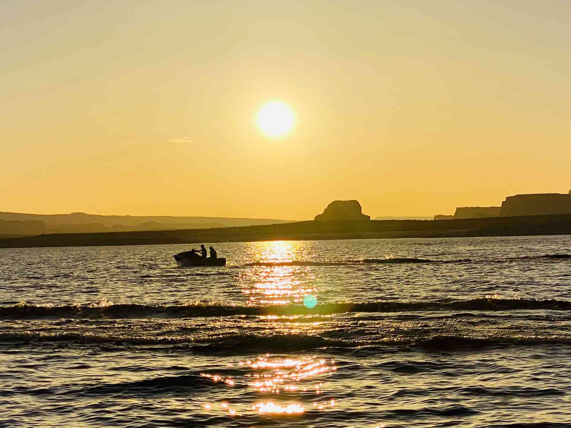 A jet ski glides across the water at sunset during a two‑hour Lake Powell Experience tour.