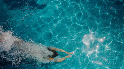 A woman dives into a domestic ecological pool with clear water.