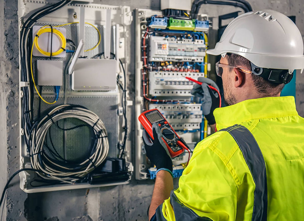 An electrical circuit breaker box with various coloured wires and a digital multimeter connected for testing.