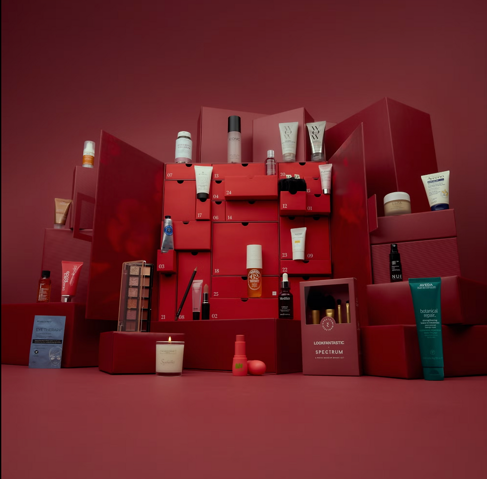 Red-themed arrangement of beauty products on stacked boxes. Includes makeup, skincare items, and visible text: "LOOKFANTASTIC,"