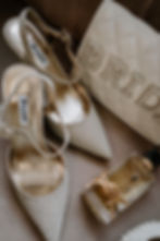 Elegant silver high heels, perfume, and a quilted clutch with "BRIDE" text. Soft, luxurious background. Mood: sophisticated.