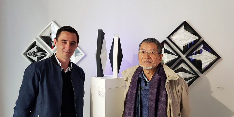 Fabrice Ainaut sur le stand de la Galerie La Ligne à Art Paris Art Fair 2018, devant ses reliefs géométriques noir et blanc, avec l'artiste Satoru Sato