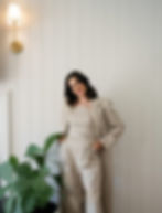Woman in a light beige suit standing by a plant