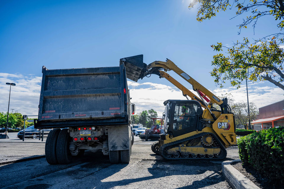 Loader dumping old asphalt in a dump truck.