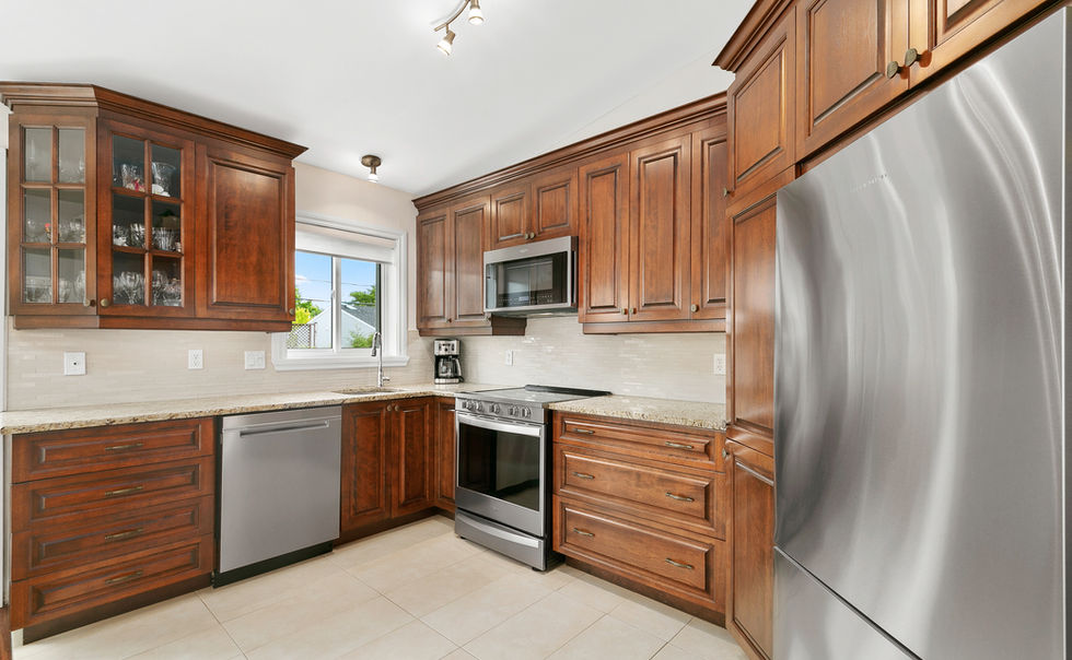 Photo intérieure d’une cuisine en bois massif avec électroménagers en inox, réalisée dans le cadre d’une mise en marché immobilière d’une maison chaleureuse et fonctionnelle.