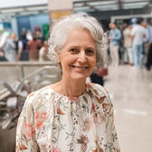 Professora Aleluia sorrindo, vestindo uma blusa florida