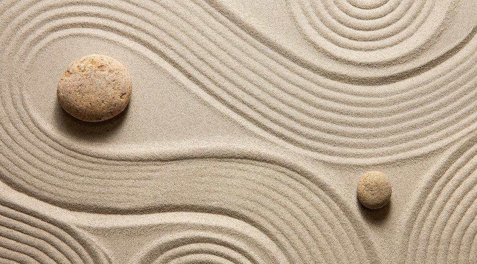 Smooth sand with flowing lines and two rounded stones arranged in a peaceful, minimalist pattern.