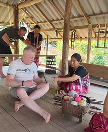 Travelers learning a traditional craft with local villagers in Northern Thailand.