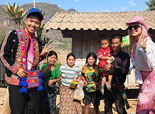 Travelers visiting a traditional hill tribe village and meeting local families in Northern Thailand.