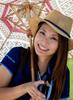 Licensed local guide Chay smiling under a traditional Northern Thai umbrella in Chiang Mai.