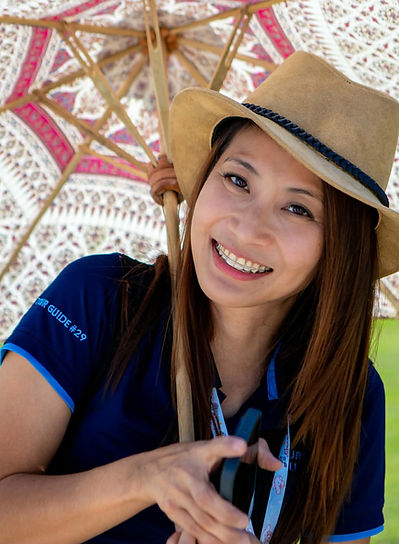 Licensed local guide Chay smiling under a traditional Northern Thai umbrella in Chiang Mai.
