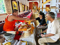 Travelers receiving a traditional Buddhist blessing at a Chiang Mai temple.