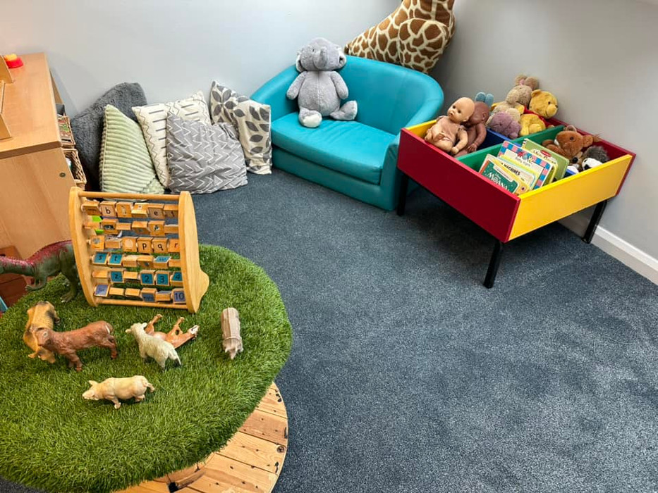 comfy chair, book shelf and play table with play animals and abacus