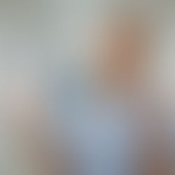 A smiling female healthcare worker in scrubs holds a phone displaying a rising financial graph. She clenches her fist triumphantly in a hospital hallway.