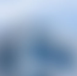 La imagen muestra un edificio moderno de la compañía Amgen, con una fachada blanca y grandes ventanales de color azul. El logo de la empresa está visible en la esquina superior, bajo un cielo azul con nubes.