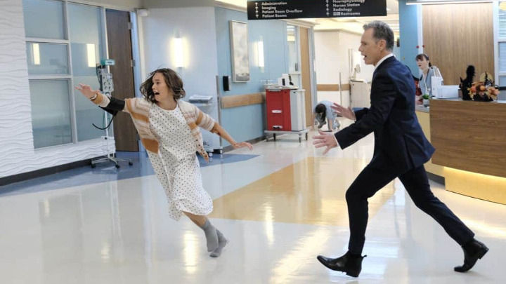 In a chaotic hospital hallway, a terrified young patient in a gown runs away from a man in a dark suit. This dramatic scene from The Resident captures a high-stakes moment of panic and pursuit.