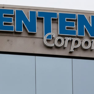 Esta imagen muestra un primer plano del letrero de Centene Corporation en lo alto de un moderno edificio de oficinas. Las grandes letras azules y grises del logotipo resaltan contra la fachada de ventanas reflectantes.