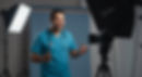 Youtuber nurse in blue scrubs with stethoscope, smiling while filming in a studio. Softbox lights illuminate the scene. Professional, upbeat mood.