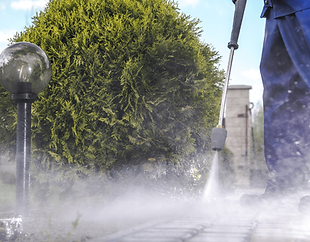 Worker pressure washing pavement, outdoor cleaning