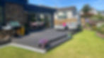 Completed composite decking terrace with planted borders beside a house