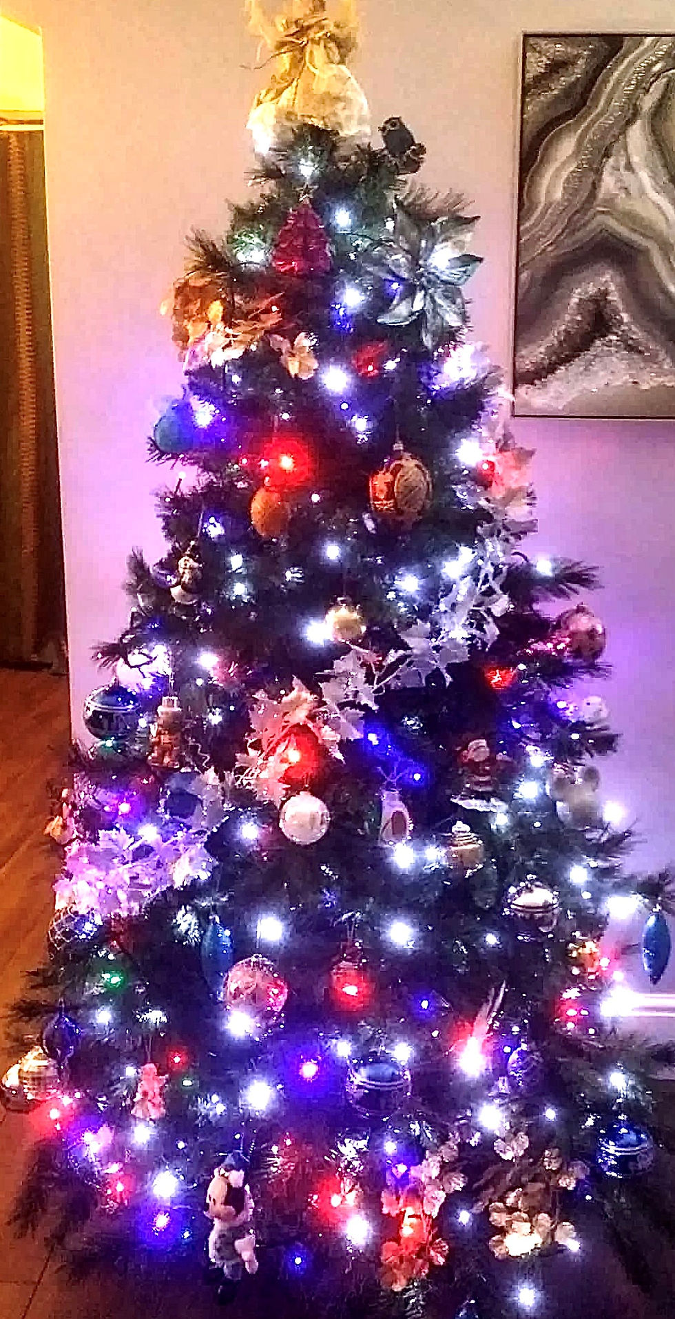 The colourful Christmas tree, photographed at night with the glow of the many colourful lights lighting up the room.