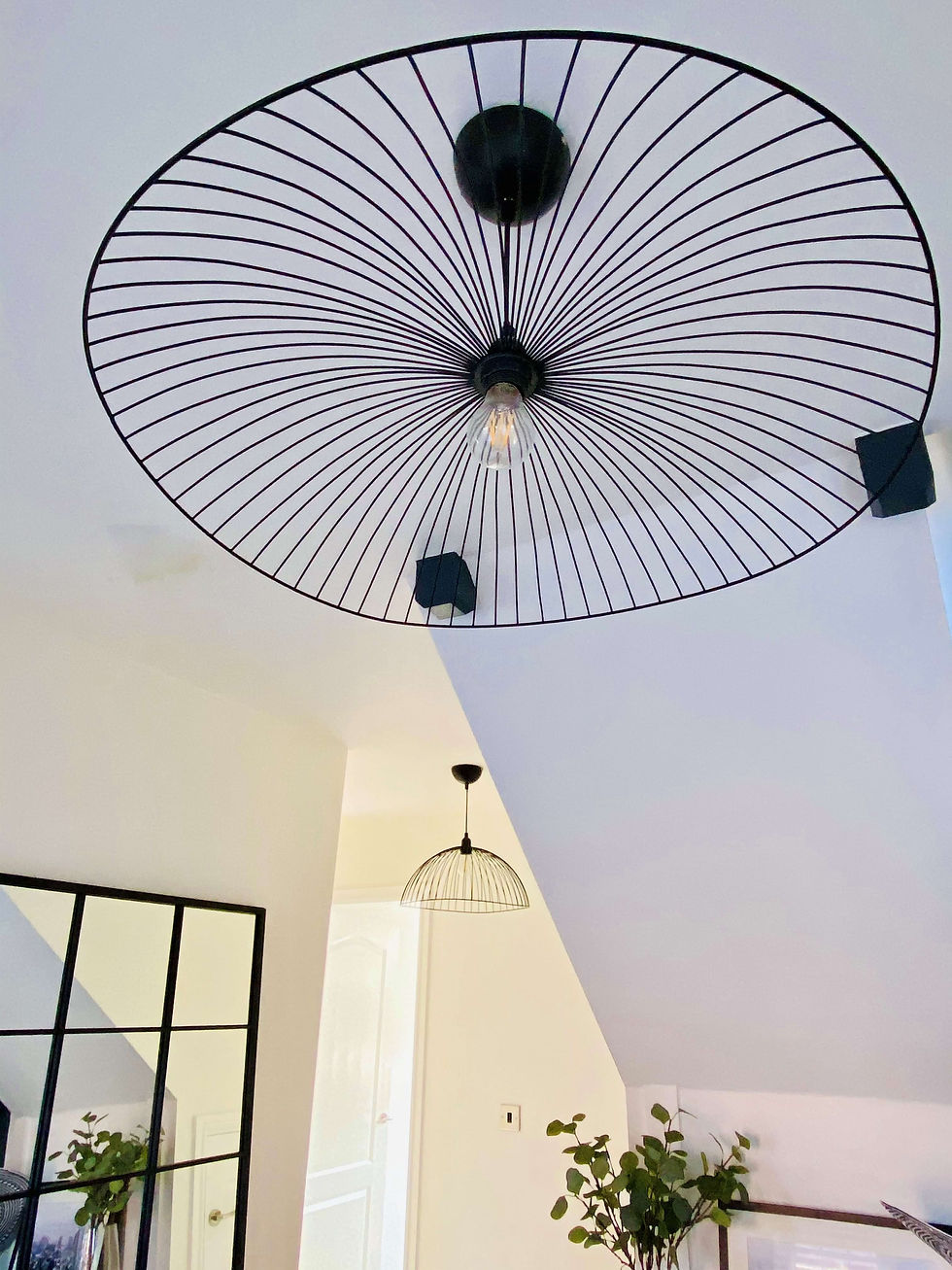 A close-up of the new over-sized black wire lampshades. The one in the foreground is flat and spread wide. The one in the background is dome shaped.