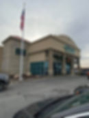 Tall internal halyard commercial flagpole with an American flag, featuring a lockable access door and winch-operated stainless steel cable system outside Prefered Auto in Fort Wayne
