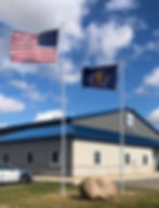 External halyard flagpole with 3” diameter and vinyl clip covers, flying a nylon 4’x6’ USA flag. & an Indiana State flag