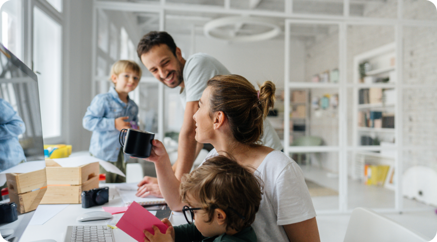 Two children are sitting at a desk with their parents.