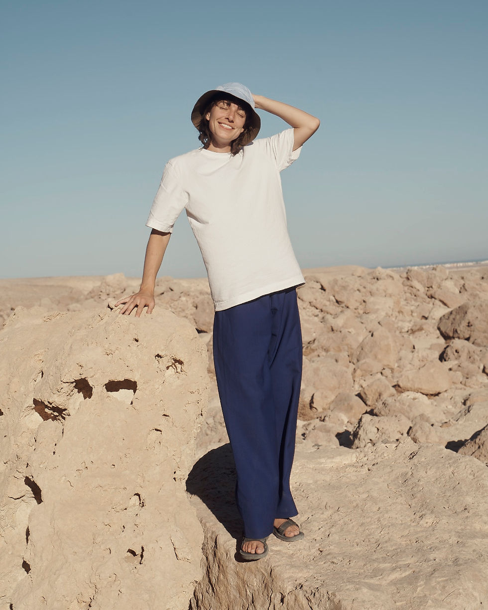 Olivia Köhler, Systemische Naturtherapeutin in der Wüste stehend mit weißem Tshirt und dunkelblauer Hose vor blauem Himmel