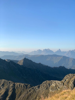 Morning atmosphere in the Alps: expansive panoramic landscape bathed in soft morning light, mountain peaks, and a peaceful atmosphere—perfect for mindful hiking and experiencing nature.