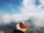 Hand holding a hard-boiled egg at the summit above the clouds – nutritious refreshment when hiking in the mountains, perfect food for day hikes