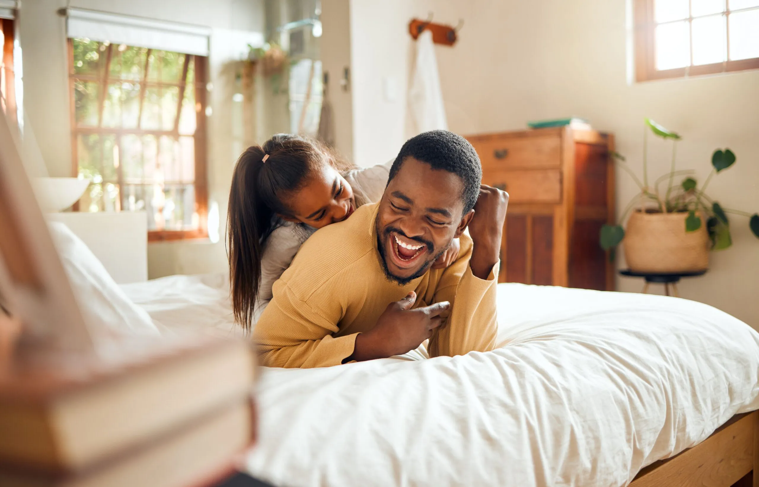 Father & Daughter laughing on bed.webp