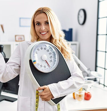 beautiful-blonde-nutritionist-woman-holding-weight-machine-balance-weight-loss-pointing-th