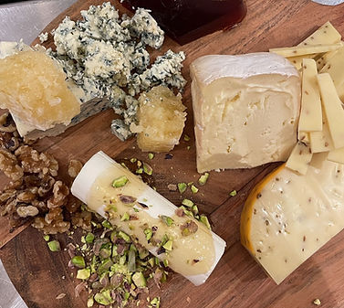 Artisan cheese selection with herbs and rustic bread slices on a wooden board