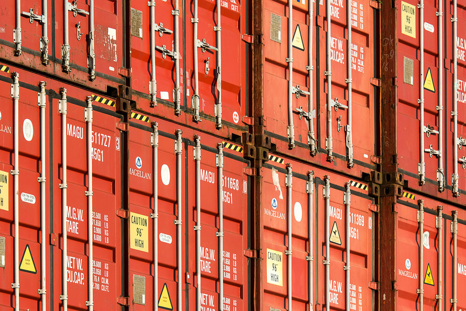 Stacked shipping containers at port representing global trade and import logistics affected by Section 122 tariffs