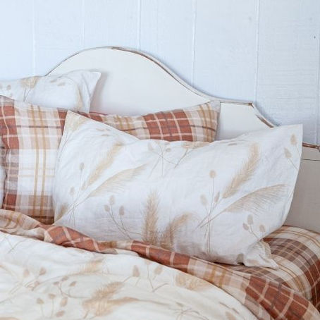 Flax linen bedding with botanical and plaid pillowcases styled on a white bed