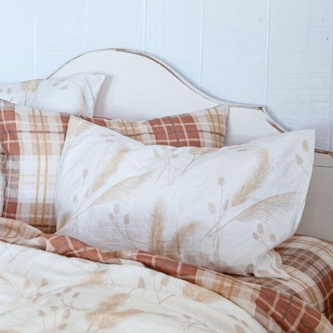 Flax linen bedding with botanical and plaid pillowcases styled on a white bed