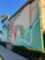 Tropical mural with pink flowers and green leaves.