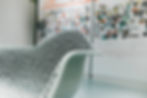 A black-and-white upholstered Eames rocker sits in front of a wall with a timeline on it. The timeline is out of focus.