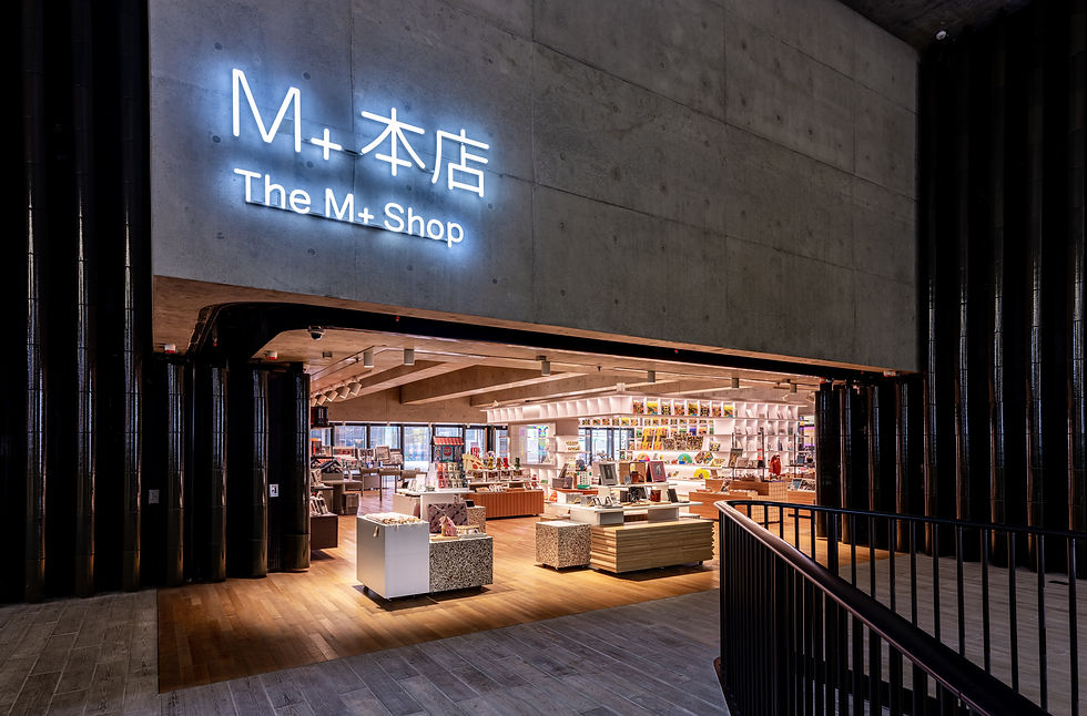 The exterior of the M+ Shop. A large concrete element holds the glowing name of the shop.