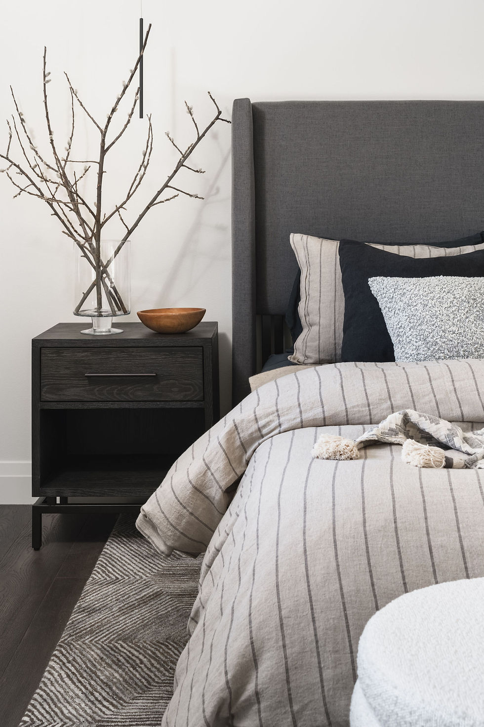 A close-up shot of a bed with various gray linens.
