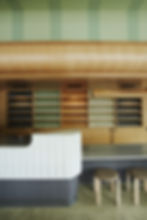 Wooden casework with rows of tea boxes. A counter in the forefront and two stools beside the counter.