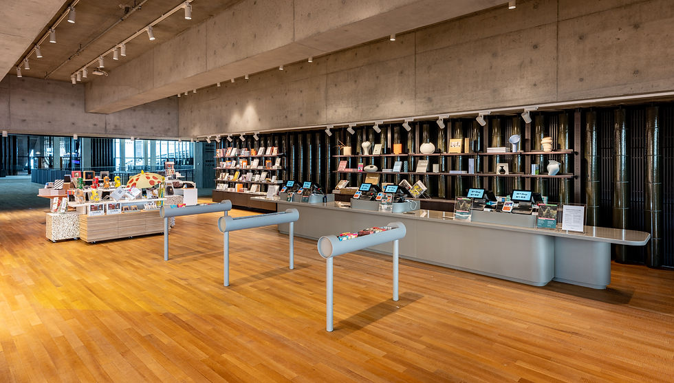 The interior of a boutique. A long wall of black shelving stands behind a cash register.