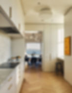 A minimal kitchen with wood floors and white cabinetry. 