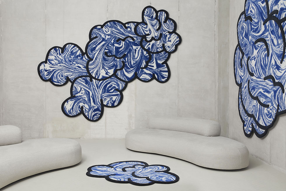 A series of cloud-shaped rugs designed by Patricia Urquiola in a gray room. Some are on the wall, one is on the floor.